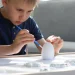 Child intensely focused on painting a plaster figurine, building cognitive skills and concentration at a table