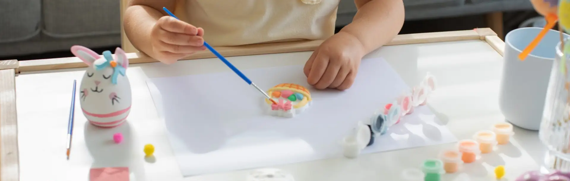 Young child painting a plaster craft kit with a fine brush at a table, improving hand-eye coordination and fine motor skills
